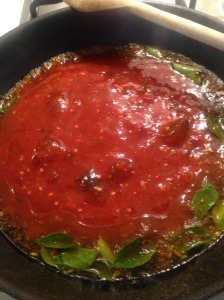 Chilli, tomato and apricot jam simmering in oil, mustard seed and curry leaf mixture